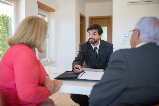 person-in-suit-talking-to-couple-over-table