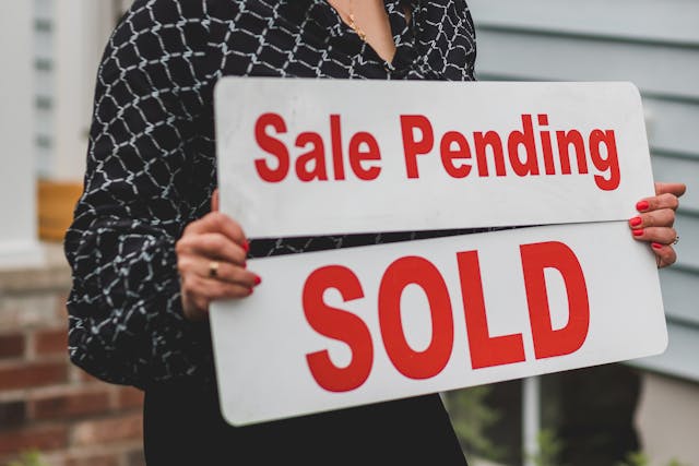 person-holding-sale-pending-and-sold-sign